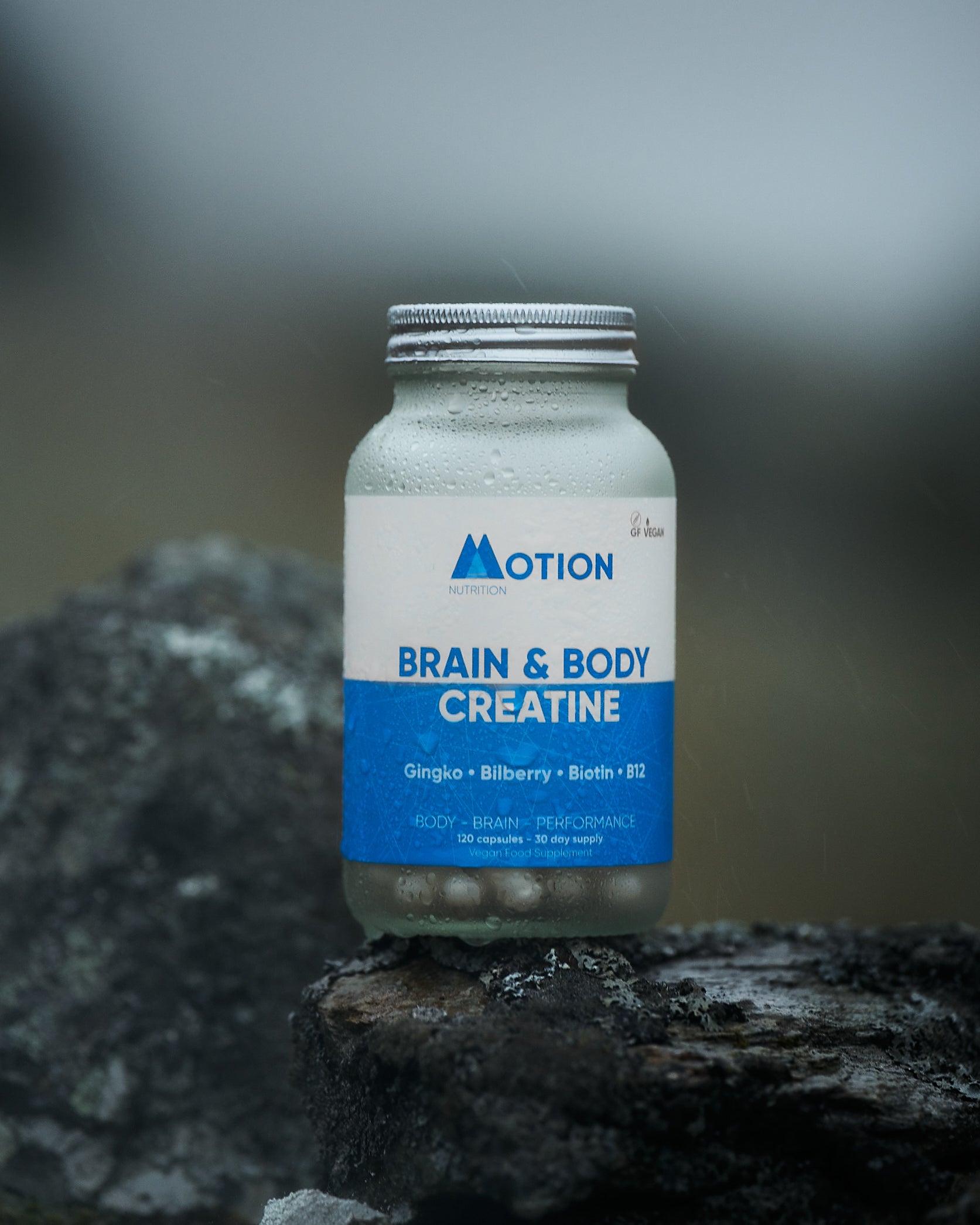Bottle of Motion Brain & Body Creatine on a rock with a blurred background